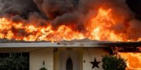Wildfire burning home roof on fire